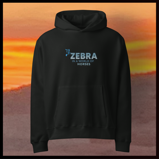 Black hoodie with 'Zebra in a World of Horses' text against an orange sunset background